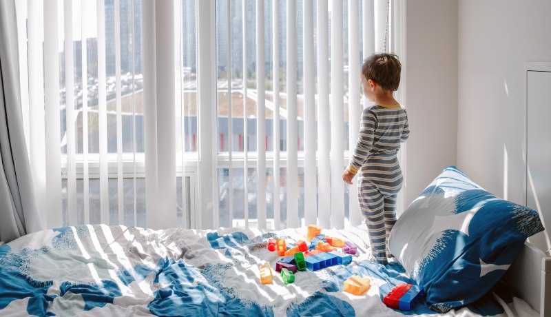 Overburdened and lonely only child myths busted! Little boy in pajamas looking out his bedroom window